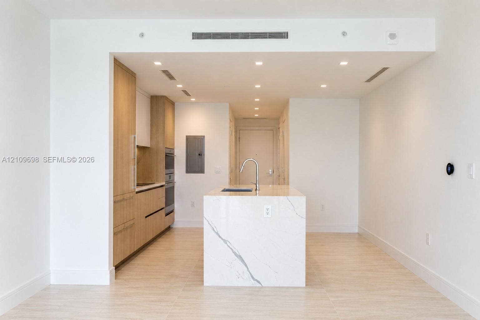 2411 Laguna Circle, #810, North Miami, FL 33181 Modern kitchen featuring light wood-finish cabinetry, a central island with a stone-finish countertop, stainless steel wall-mounted oven, and recessed lighting