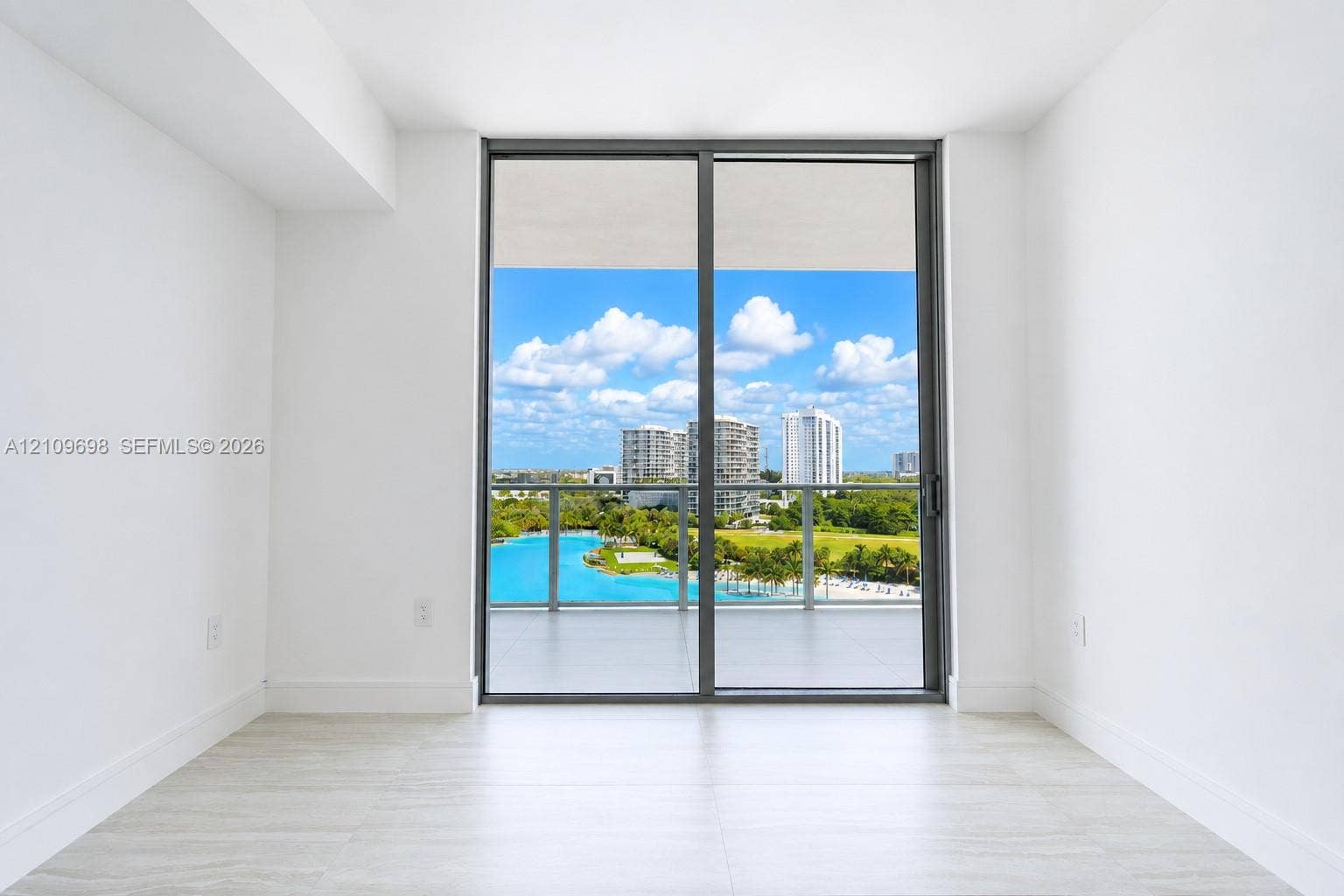 2411 Laguna Circle, #810, North Miami, FL 33181 Floor-to-ceiling sliding glass door providing access to a covered balcony with a glass railing