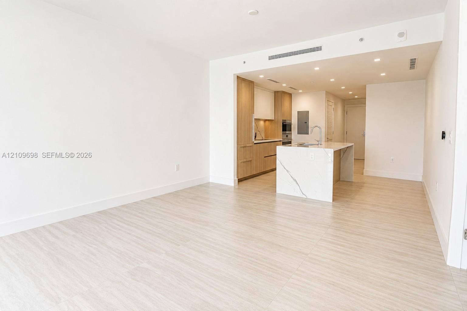 2411 Laguna Circle, #810, North Miami, FL 33181 Open-concept kitchen featuring flat-panel wood-finish cabinetry, a waterfall-edge stone island, built-in appliances, recessed lighting, and wood-finish flooring