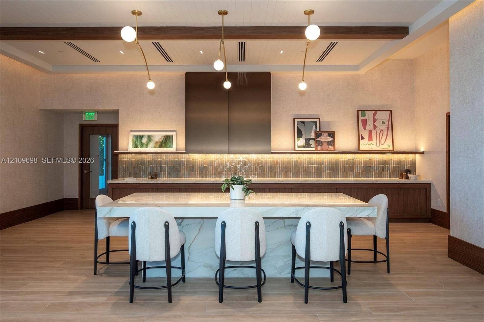 2411 Laguna Circle, #810, North Miami, FL 33181 Kitchen featuring a stone-topped island with waterfall edges, custom wood cabinetry, a full-height metallic range hood, linear accent lighting, and wood-finish flooring