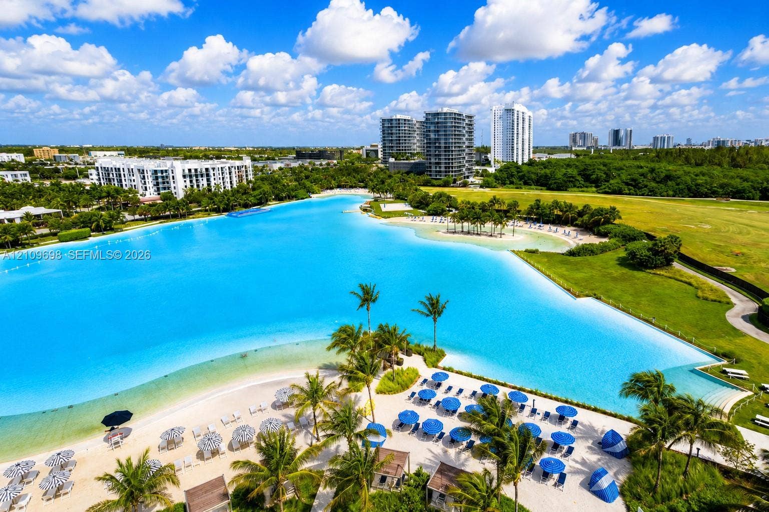 2411 Laguna Circle, #810, North Miami, FL 33181 Expansive man-made lagoon featuring a sandy beach, shoreline palm trees, and manicured green space