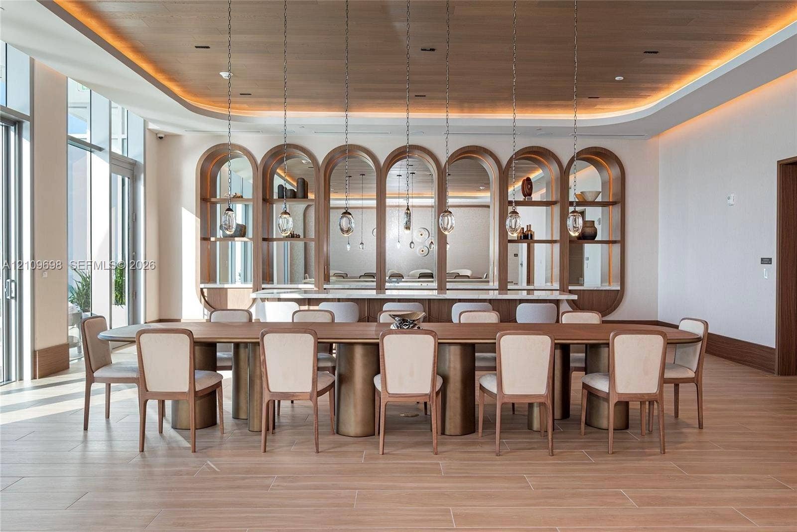 2411 Laguna Circle, #810, North Miami, FL 33181 Recessed cove lighting, wood-paneled ceiling, arched built-in shelving with integrated mirrors, floor-to-ceiling windows, and wood-finish tile flooring