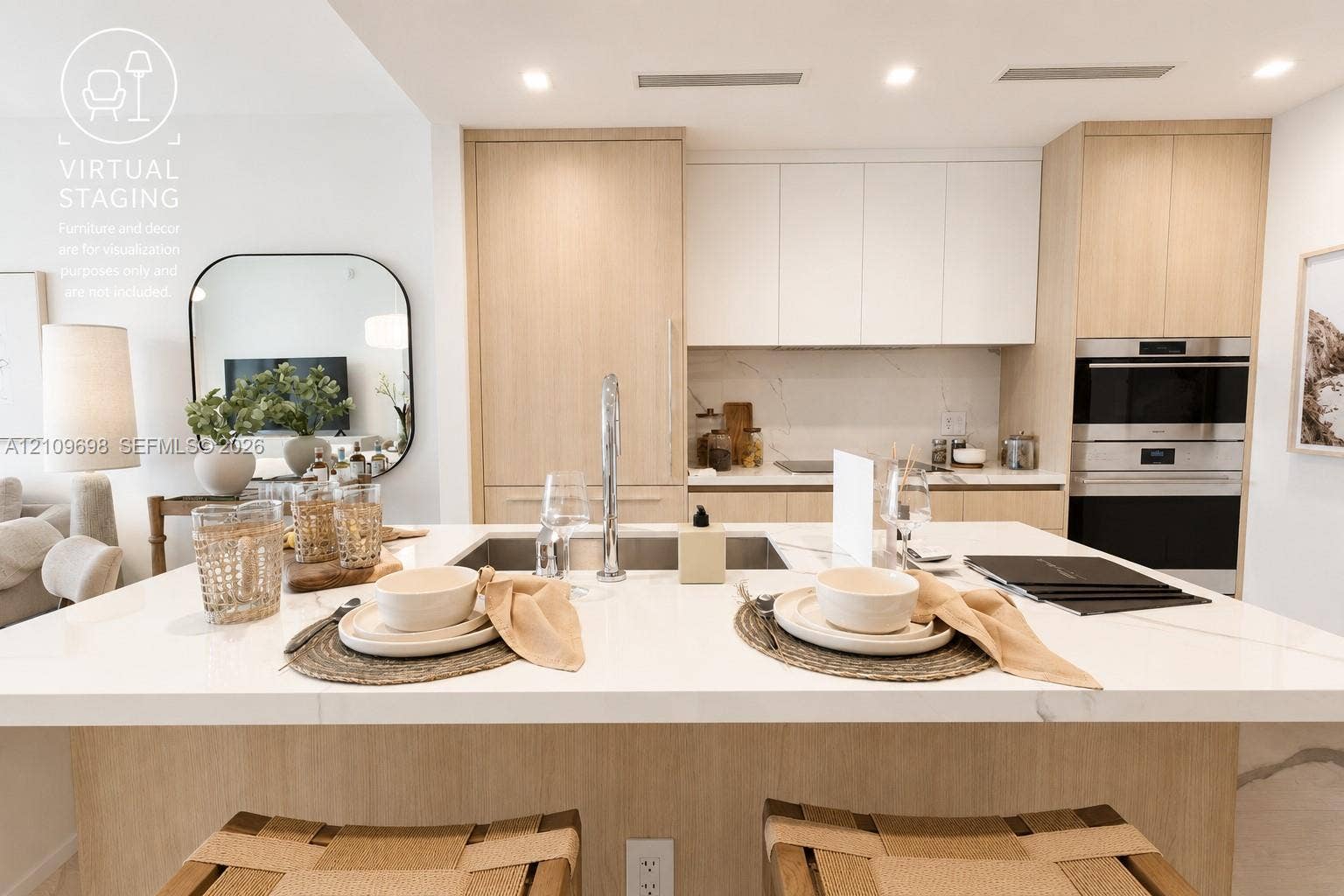 2411 Laguna Circle, #810, North Miami, FL 33181 Kitchen featuring an island with a light-toned countertop, custom light-wood cabinetry, matte-finish wall cabinetry, an integrated stainless steel wall oven, and a sleek undermount kitchen sink