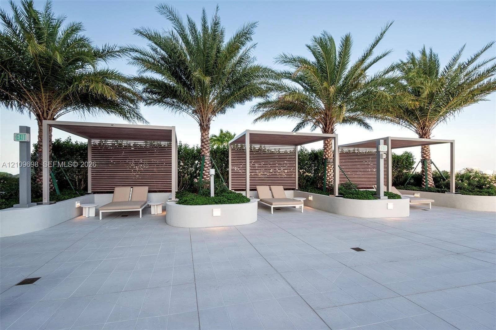 2411 Laguna Circle, #810, North Miami, FL 33181 Outdoor terrace featuring large-format paver tiles, built-in curved concrete planters, structural shade pergolas, and integrated privacy screens
