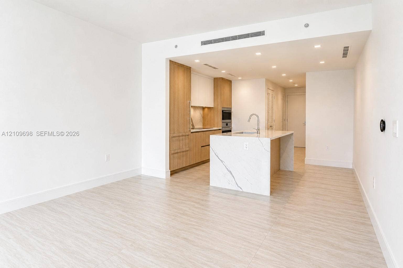 2411 Laguna Circle, #810, North Miami, FL 33181 Kitchen featuring wood-finish cabinetry, stone-surface waterfall island with an undermount sink, built-in appliances, recessed lighting, and tile flooring