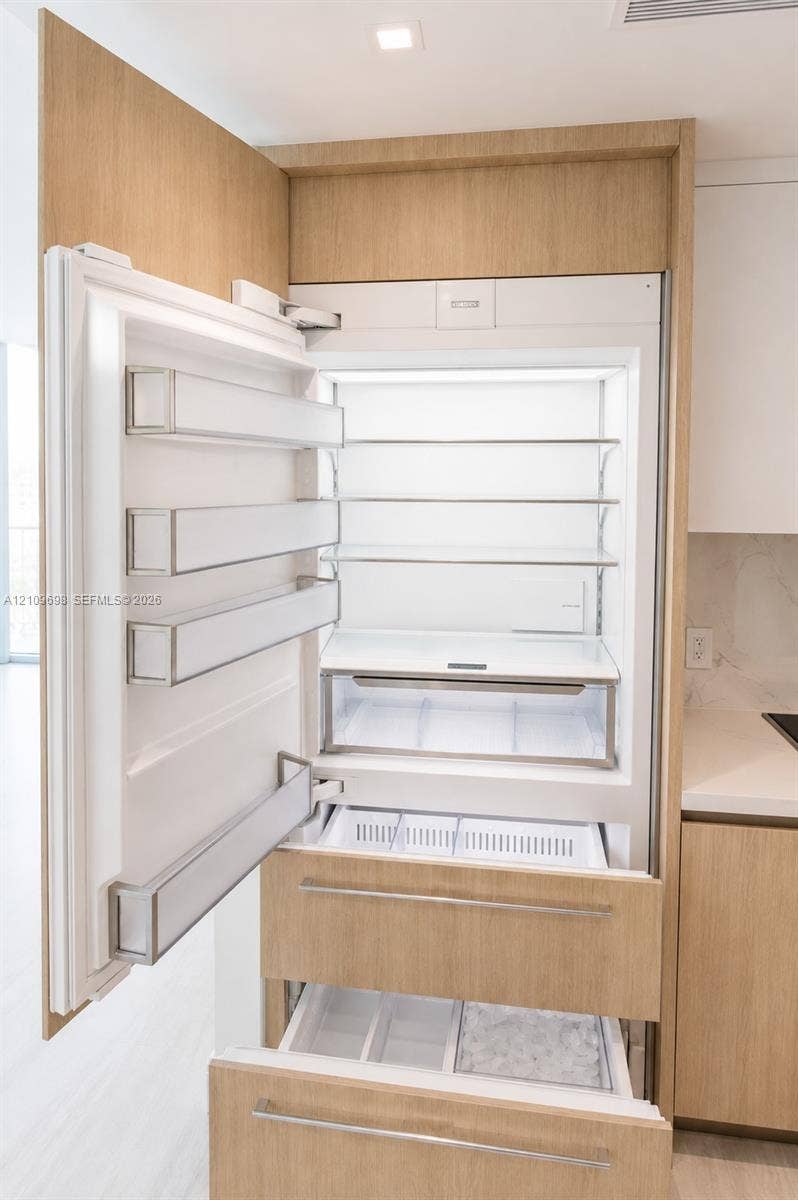 2411 Laguna Circle, #810, North Miami, FL 33181 Integrated refrigerator featuring custom wood-finish cabinetry panels, adjustable shelving, tiered pull-out freezer drawers, and recessed lighting