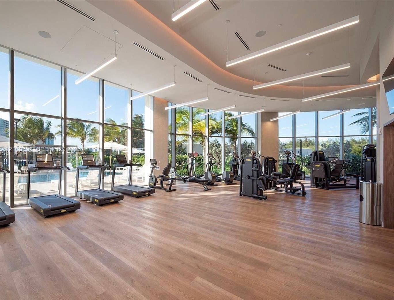 2411 Laguna Circle, #810, North Miami, FL 33181 Fitness facility featuring floor-to-ceiling windows, wood-finish flooring, curved architectural ceiling detail, and recessed linear lighting
