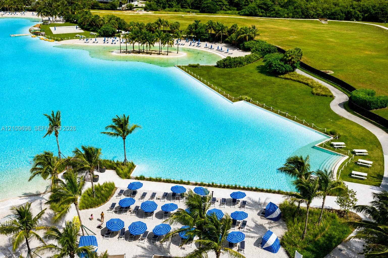 2411 Laguna Circle, #810, North Miami, FL 33181 Man-made lagoon featuring a white sand beach, extensive perimeter landscaping, walking paths, and concrete terraced stairs leading to the water