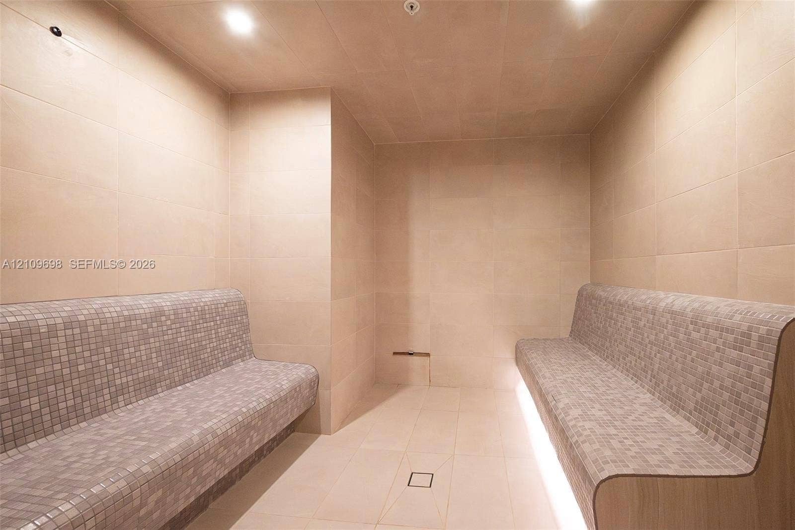 2411 Laguna Circle, #810, North Miami, FL 33181 Sauna featuring floor-to-ceiling tile, dual built-in benches with mosaic tile finish, under-bench ambient lighting, and recessed ceiling lighting