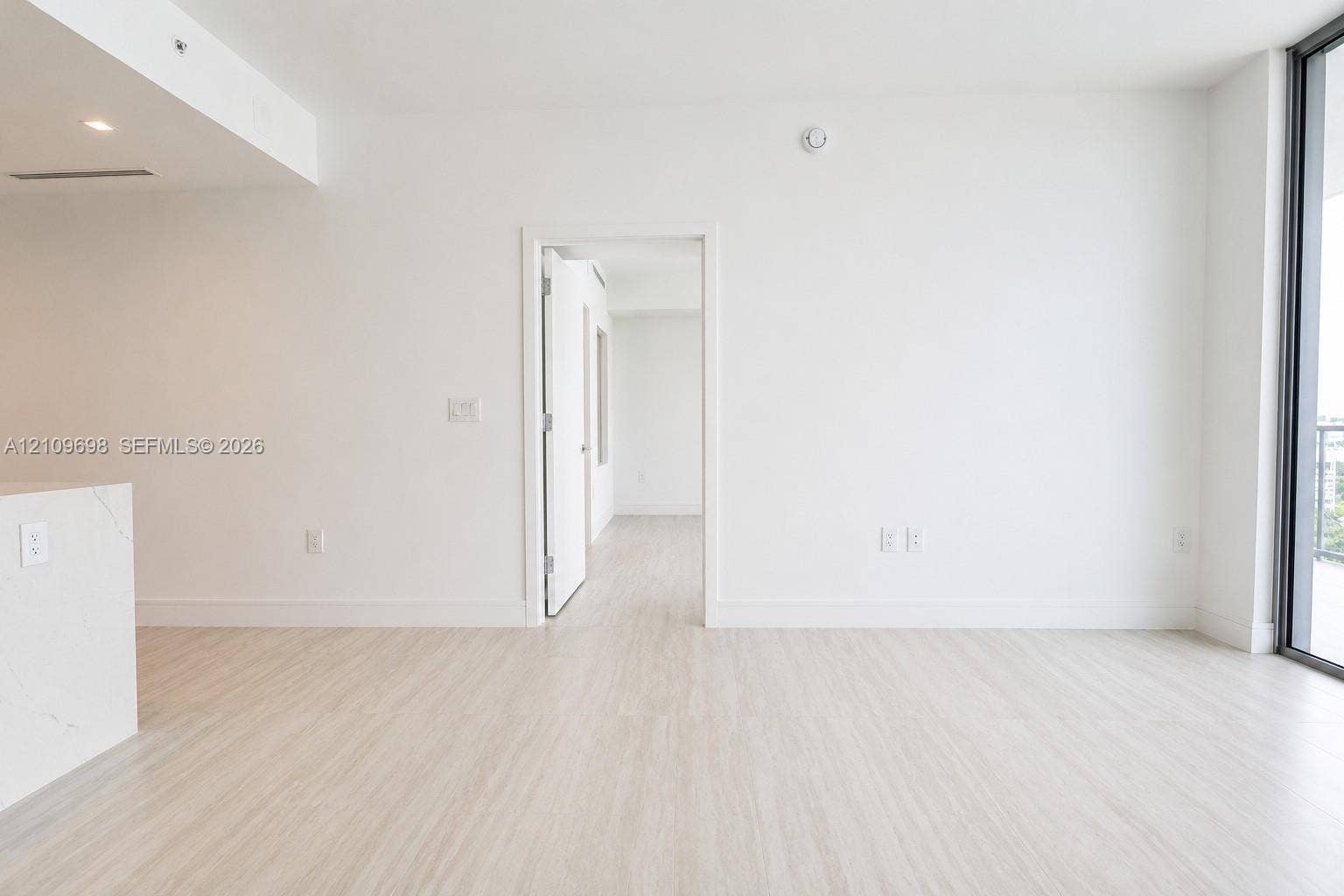 2411 Laguna Circle, #810, North Miami, FL 33181 Interior space featuring wood-finish flooring, floor-to-ceiling glass panel door, and white solid-surface peninsula countertop