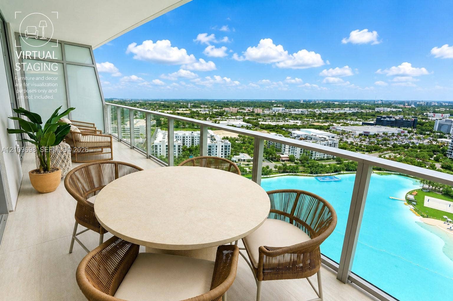 2411 Laguna Circle, #810, North Miami, FL 33181 Covered balcony featuring large-format tile flooring and a sleek metal railing with glass panels, overlooking a prominent turquoise lagoon and expansive horizon