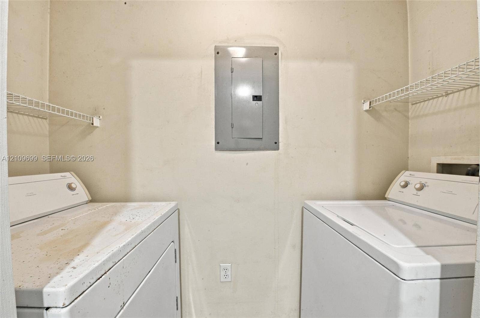 Utility space featuring wall-mounted wire shelving and a centrally located electrical panel