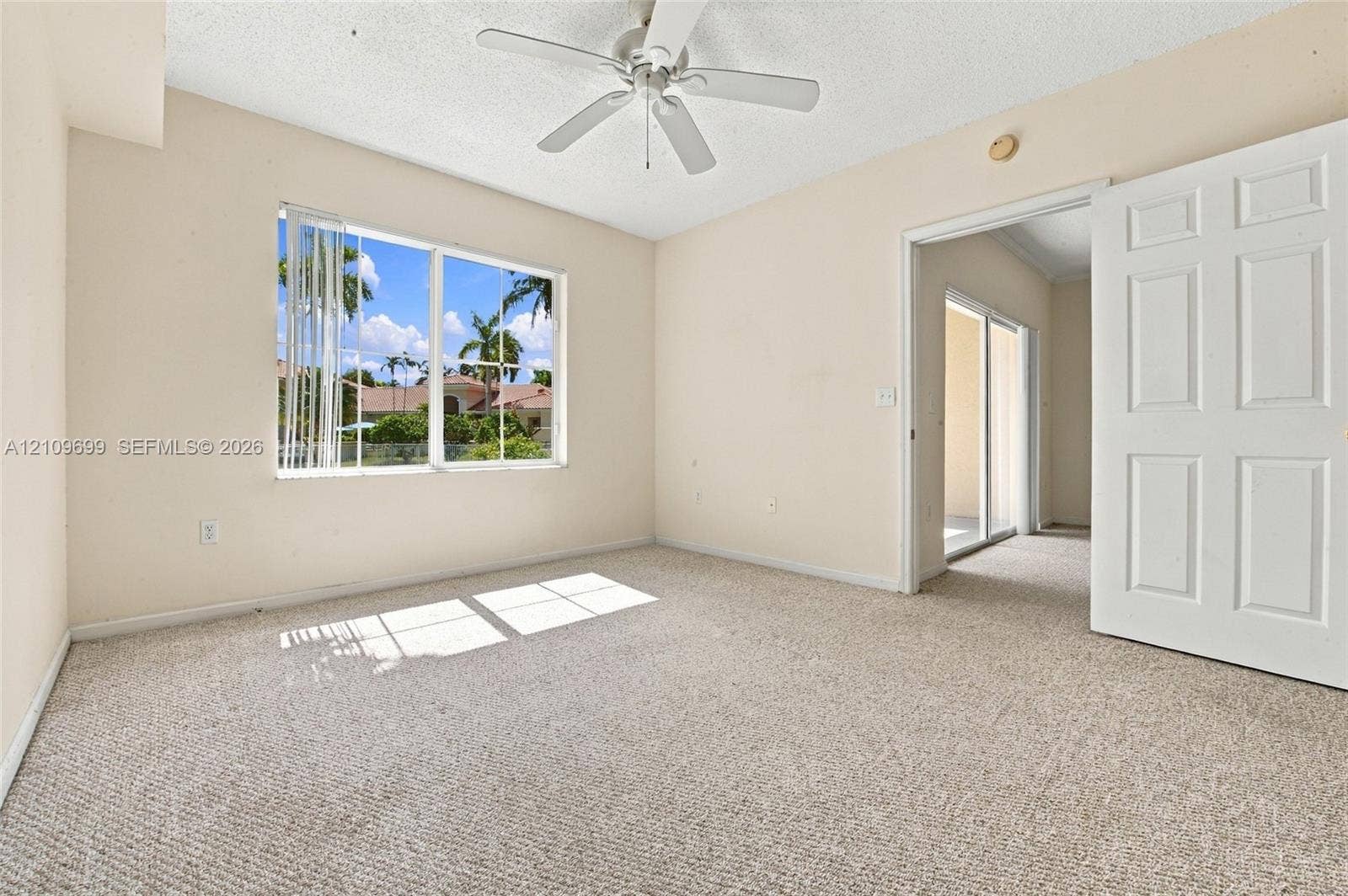 Interior space featuring neutral-toned carpeting, a multi-blade ceiling fan, and a large sliding glass door