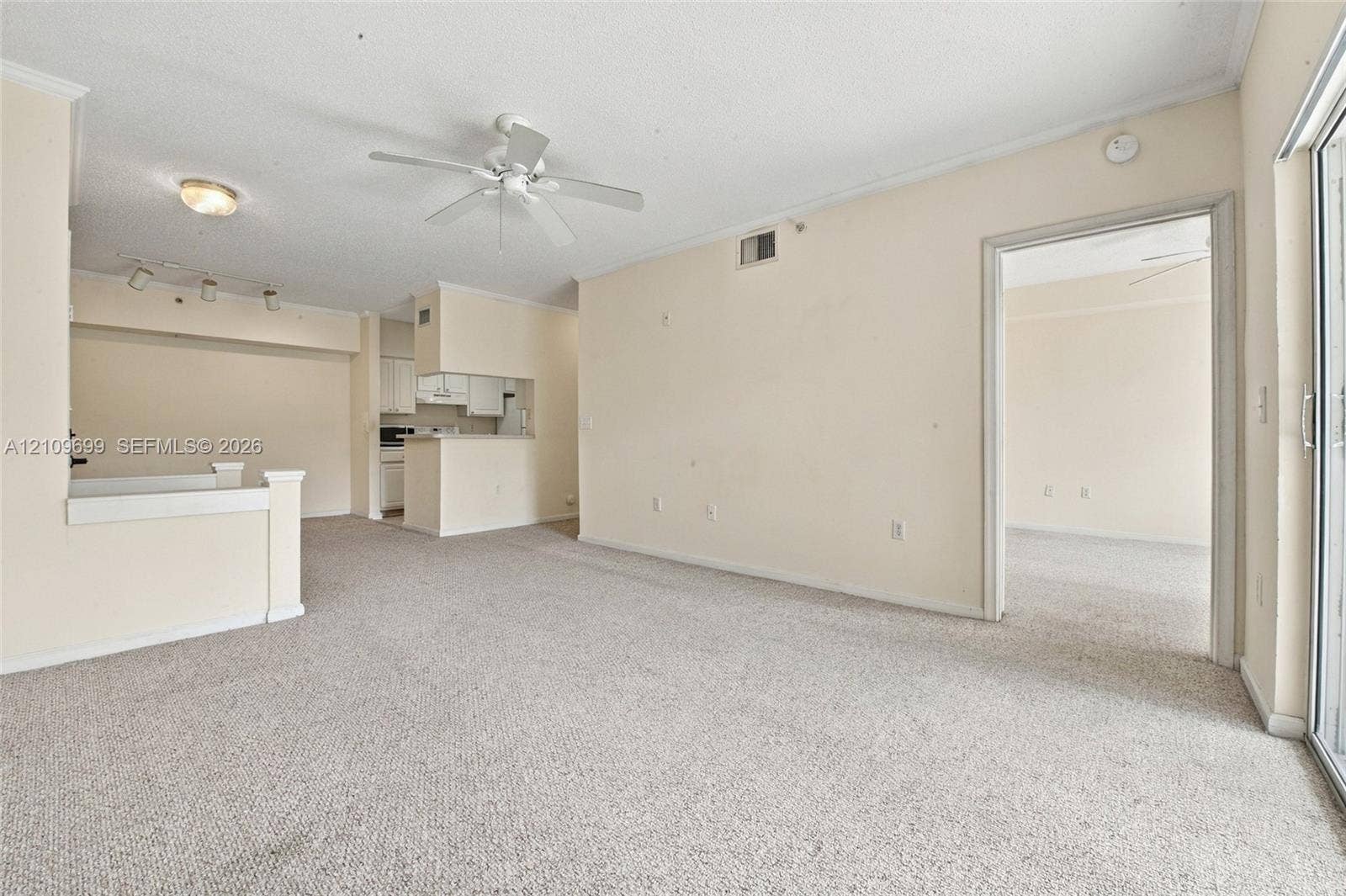 Open-concept interior featuring wall-to-wall carpeting, a ceiling fan, sliding glass door, and recessed track lighting