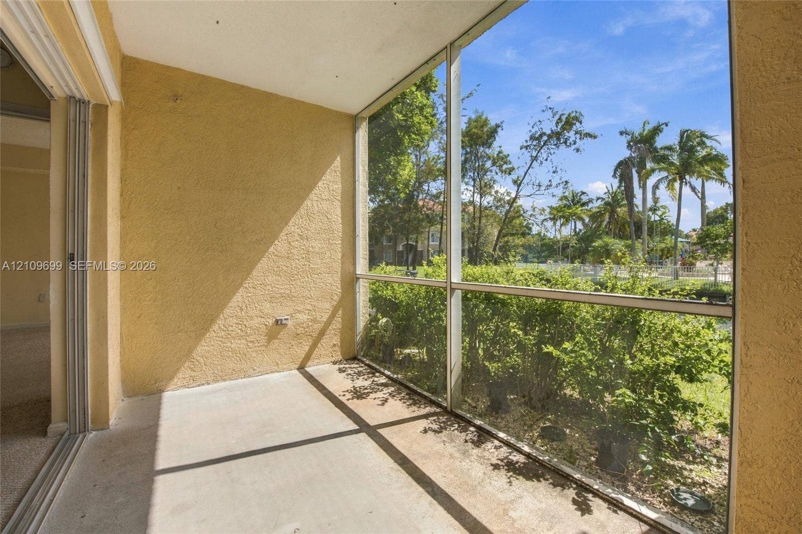 Screened-in patio featuring concrete flooring, textured stucco walls, and aluminum frame enclosures
