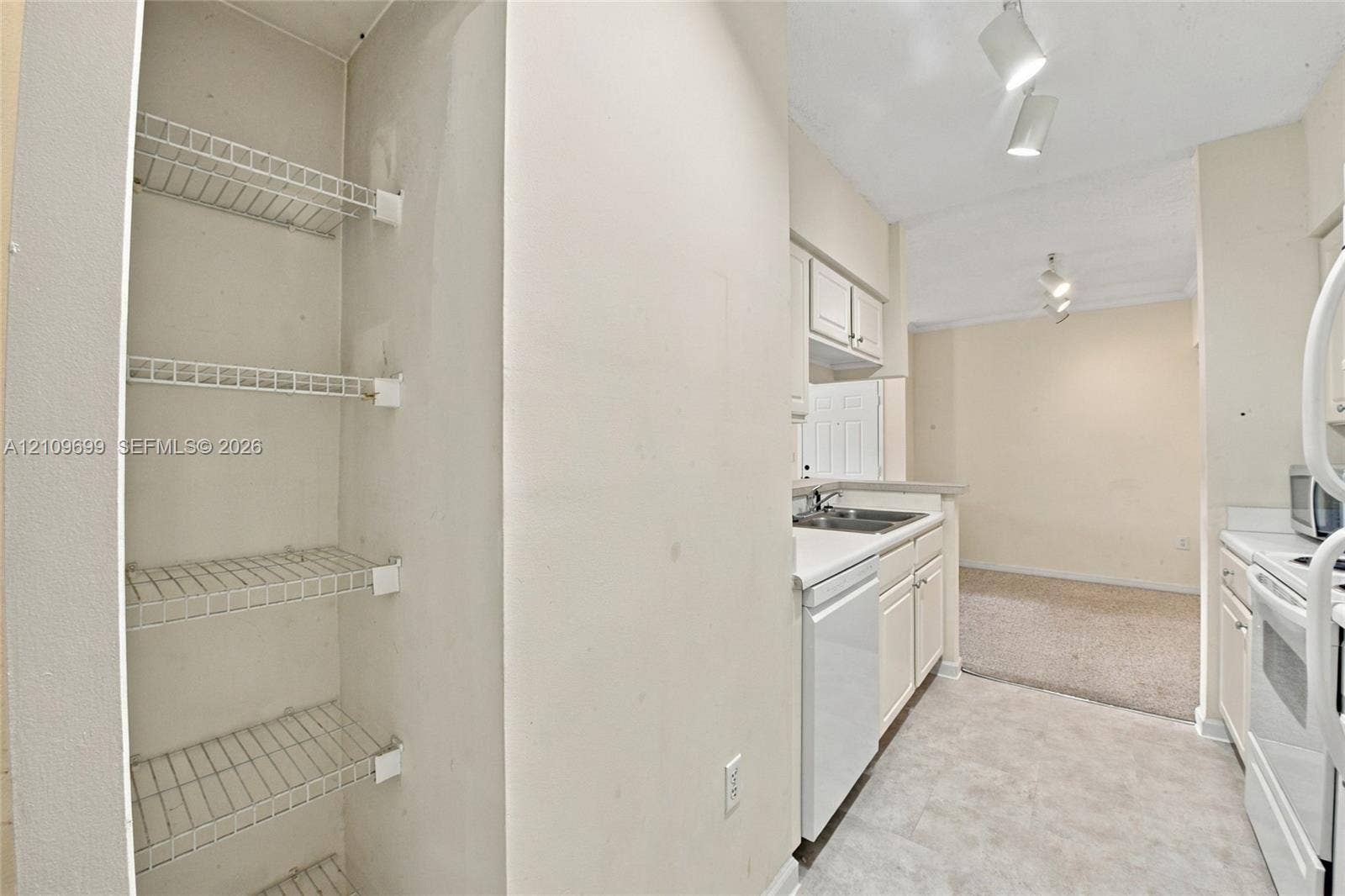 Kitchen featuring white cabinetry, wire shelving, tile flooring, and integrated track lighting
