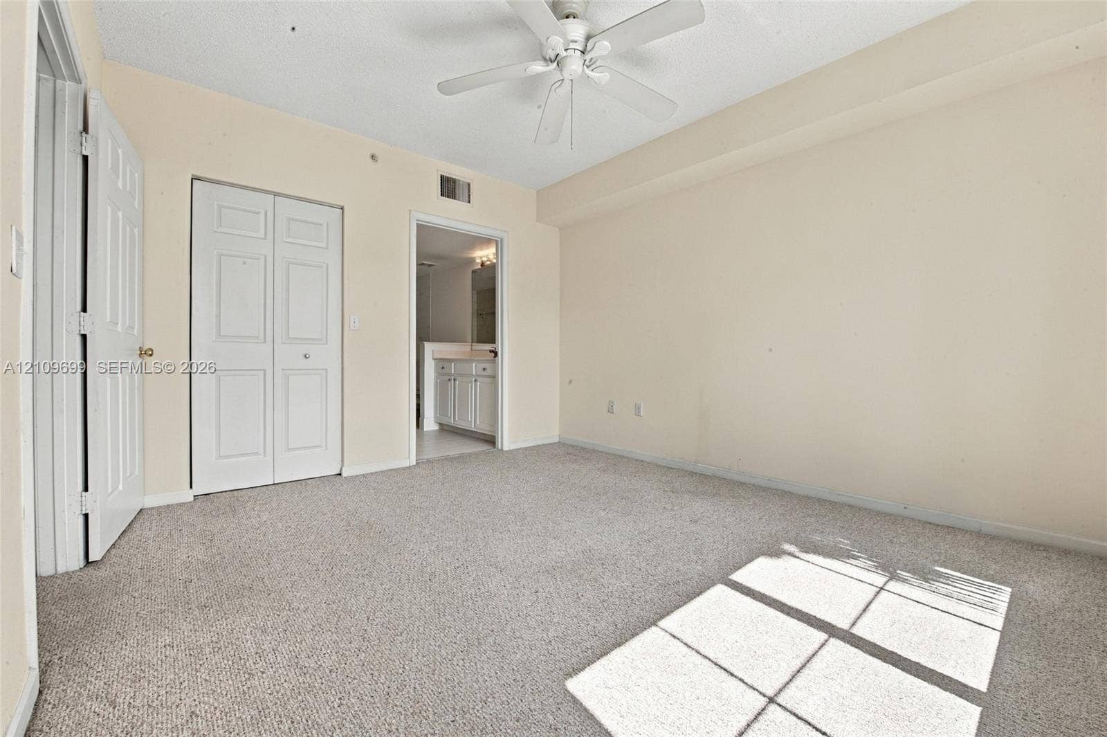 Neutral-toned room featuring neutral carpeting, a ceiling fan, and double-door closet storage