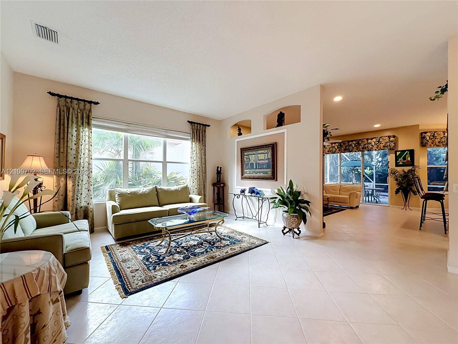 Living area featuring large windows, recessed wall niches, tile flooring, and sliding glass doors