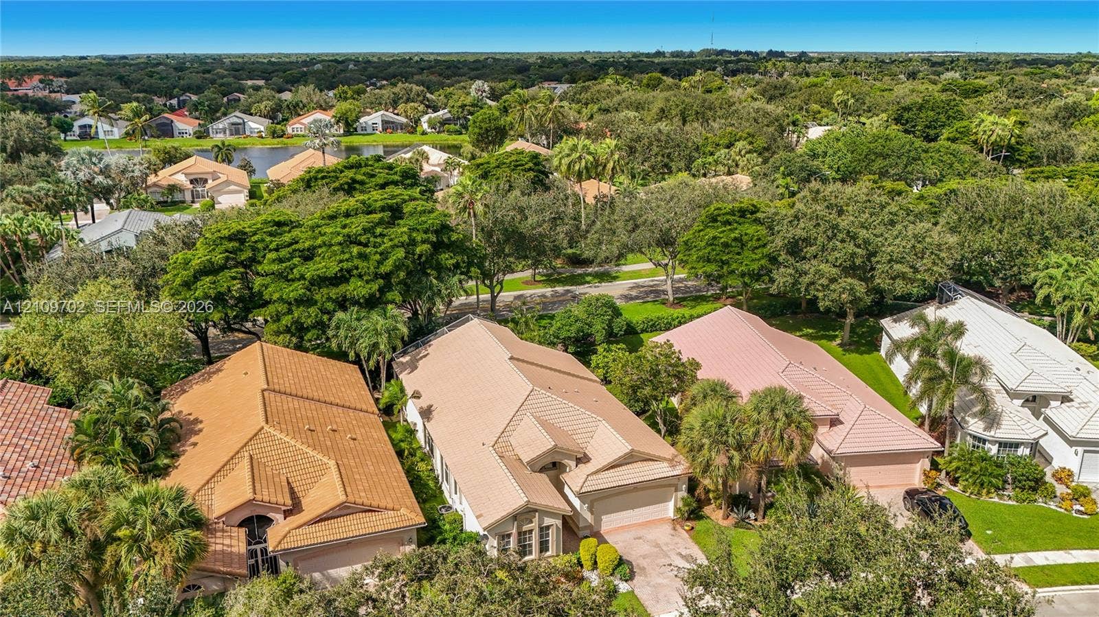 Aerial perspective featuring tile-roofed residences, paved driveways, mature canopy trees, and established landscaping