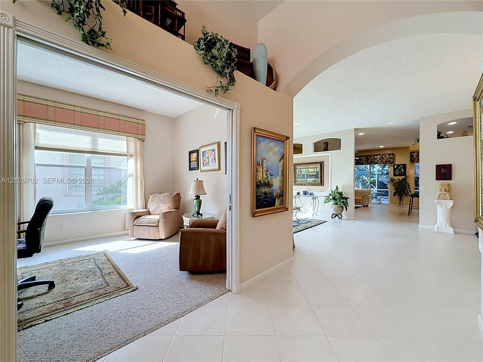 Interior featuring high ceilings with architectural niches, tile flooring, and arched room entryways