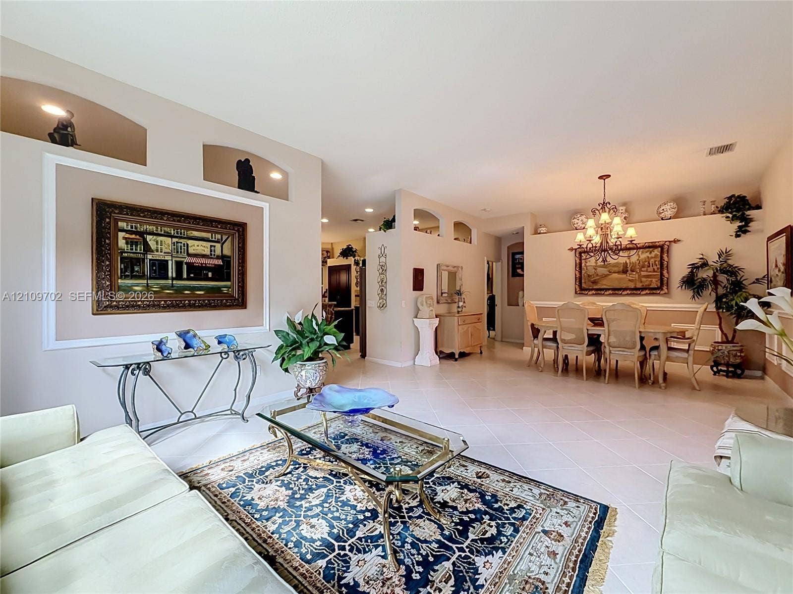 Open-concept interior featuring high ceilings, decorative wall niches, ceramic tile flooring, and an ornate chandelier