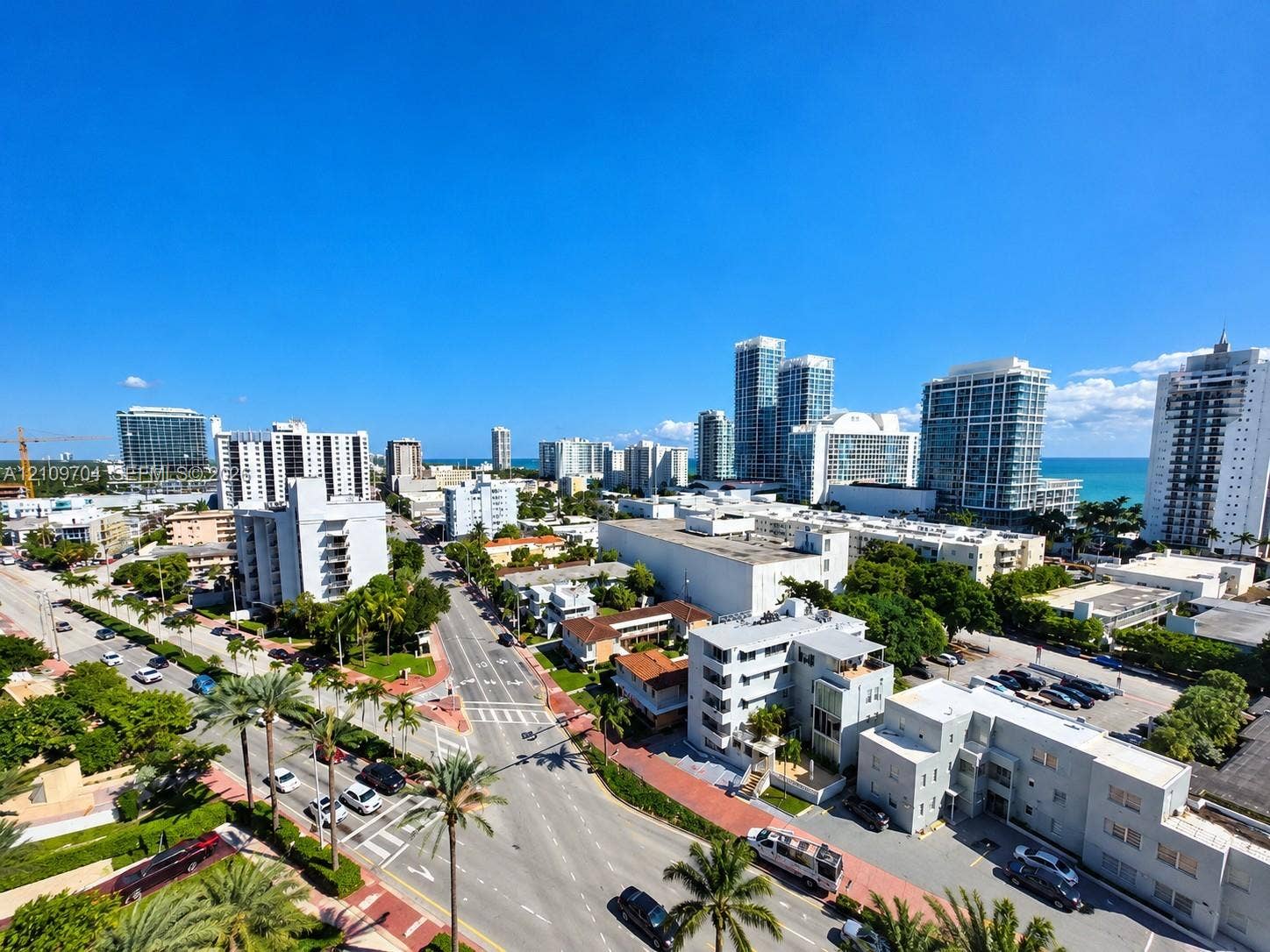 6770 Indian Creek Drive, #14C, Miami Beach, FL 33141 Elevated aerial perspective of a coastal cityscape featuring high-rise buildings, urban thoroughfares, tropical palm tree landscaping, and coastal waters on the horizon