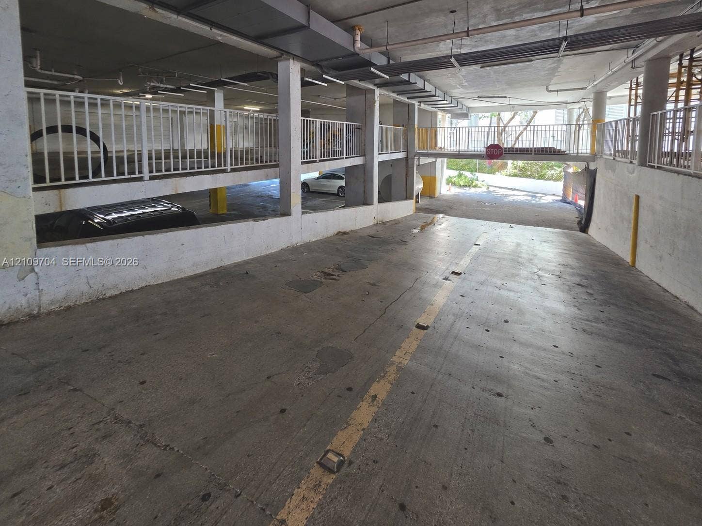 6770 Indian Creek Drive, #14C, Miami Beach, FL 33141 Multi-level parking structure featuring a concrete ramp, steel railings, and overhead lighting