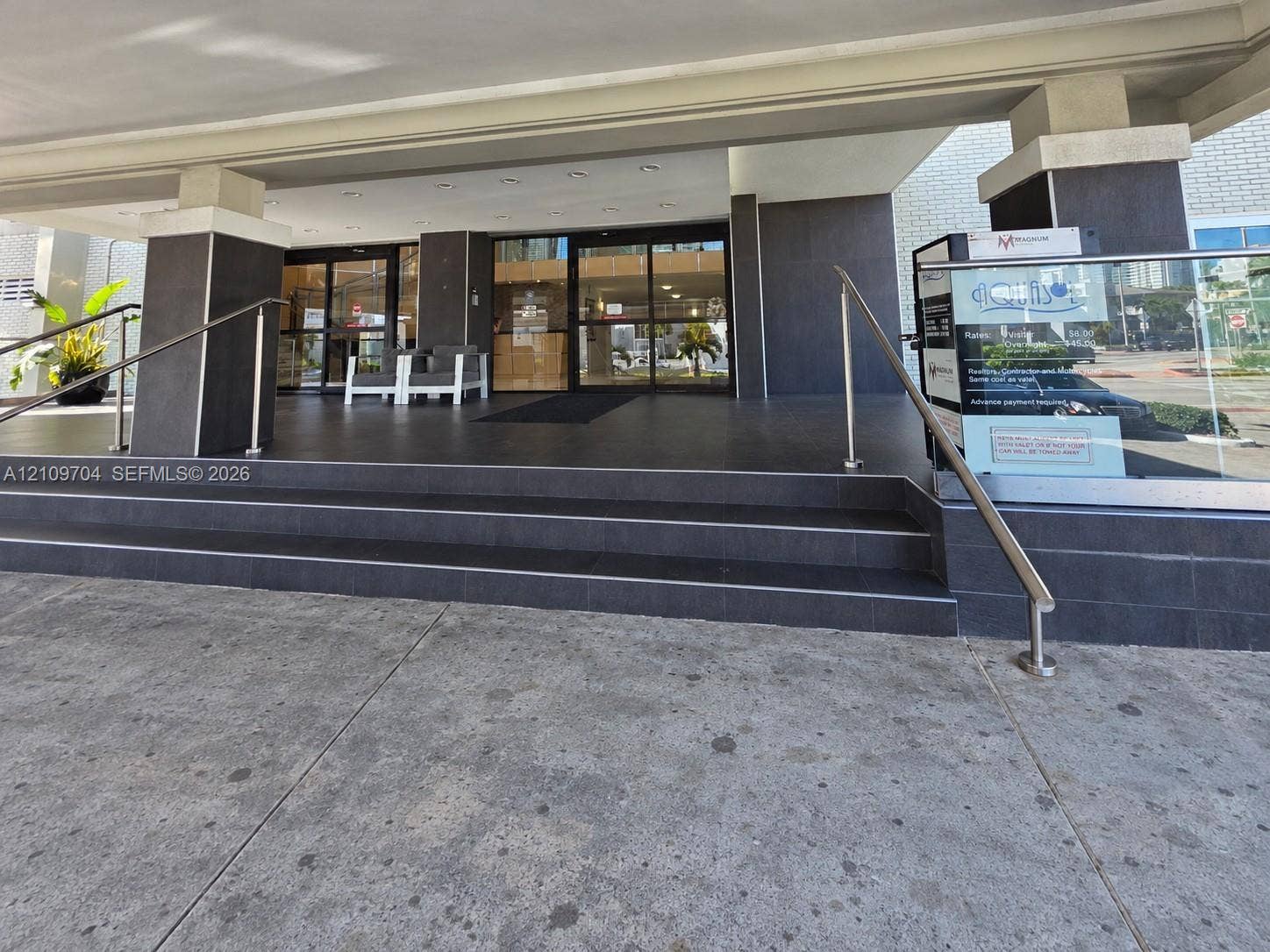 6770 Indian Creek Drive, #14C, Miami Beach, FL 33141 Covered building entrance featuring tiered stone steps, matte dark tile finishes, and stainless steel handrails