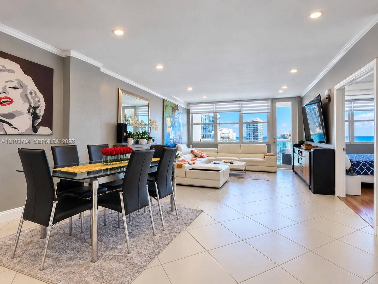 6770 Indian Creek Drive, #14C, Miami Beach, FL 33141 Open-concept floor plan featuring large-format ceramic tile flooring, recessed lighting, crown molding, and floor-to-ceiling windows with balcony access