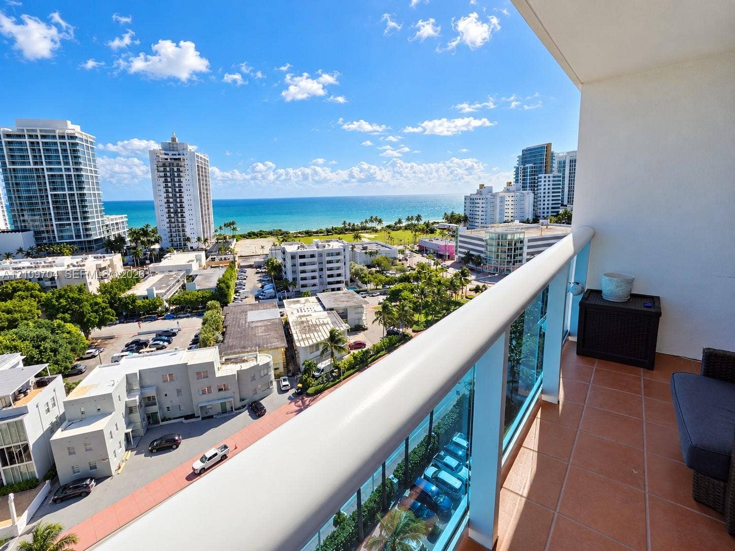 6770 Indian Creek Drive, #14C, Miami Beach, FL 33141 Covered balcony featuring terracotta-style tile flooring and a glass-panel railing overlooking the ocean and urban coastline