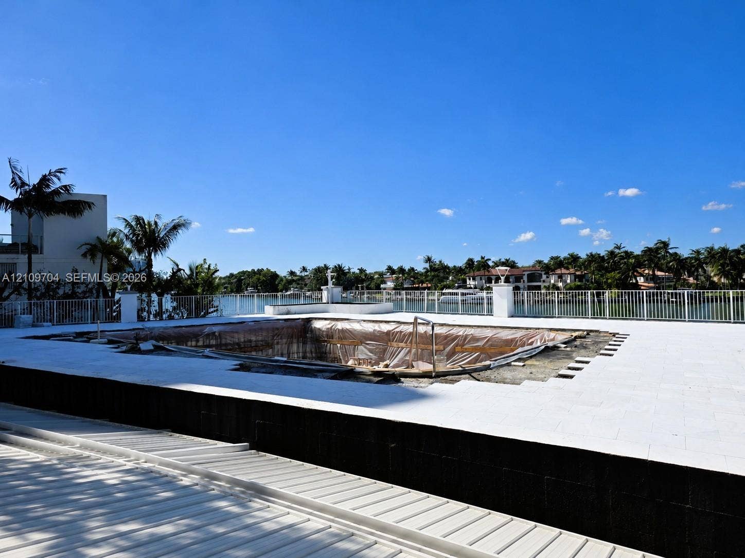 6770 Indian Creek Drive, #14C, Miami Beach, FL 33141 Waterfront terrace featuring a tiled deck, perimeter metal fencing, and a pool basin under construction