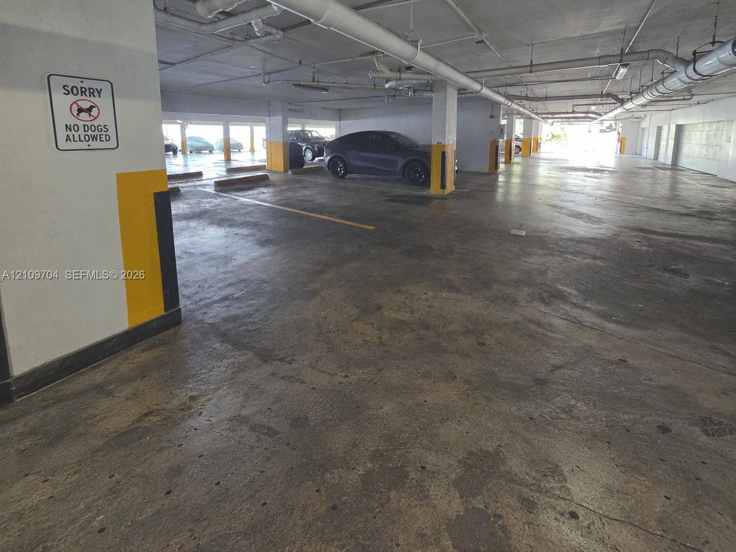 6770 Indian Creek Drive, #14C, Miami Beach, FL 33141 Covered parking area featuring concrete flooring, structural support columns, and overhead utility systems