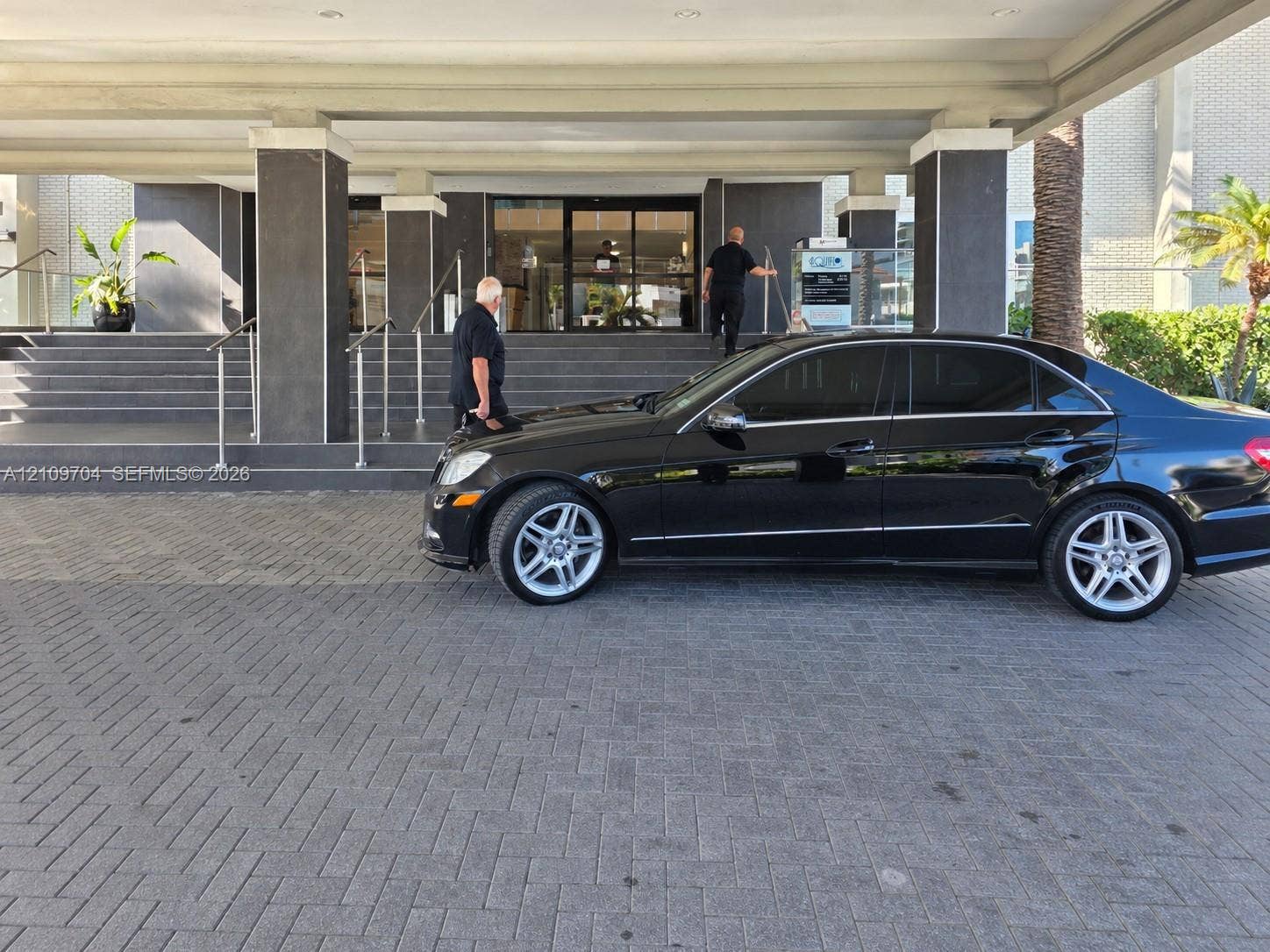 6770 Indian Creek Drive, #14C, Miami Beach, FL 33141 Covered drive-up entrance featuring a stone-paver motor court, concrete stairs, and glass-entry doors with metallic handrails