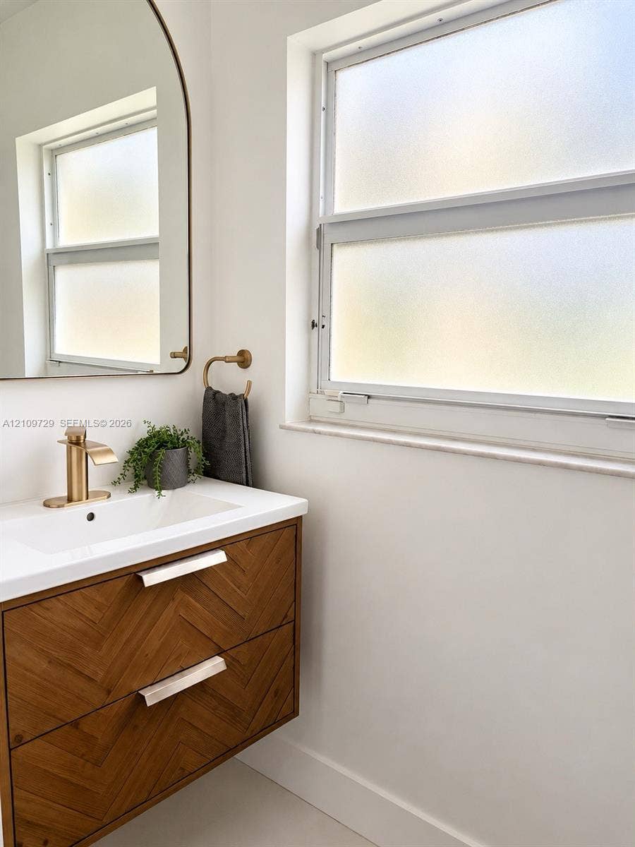 12665 SW 54th Court, Miramar, FL 33027 Wall-mounted vanity featuring a chevron-patterned wood-finish exterior, integrated white sink, metallic-finish faucet, and arched mirror