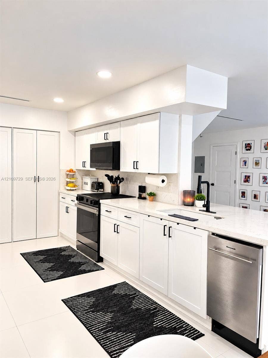 12665 SW 54th Court, Miramar, FL 33027 Kitchen featuring white cabinetry with matte black hardware, stone-finish countertops, recessed lighting, and a stainless steel dishwasher