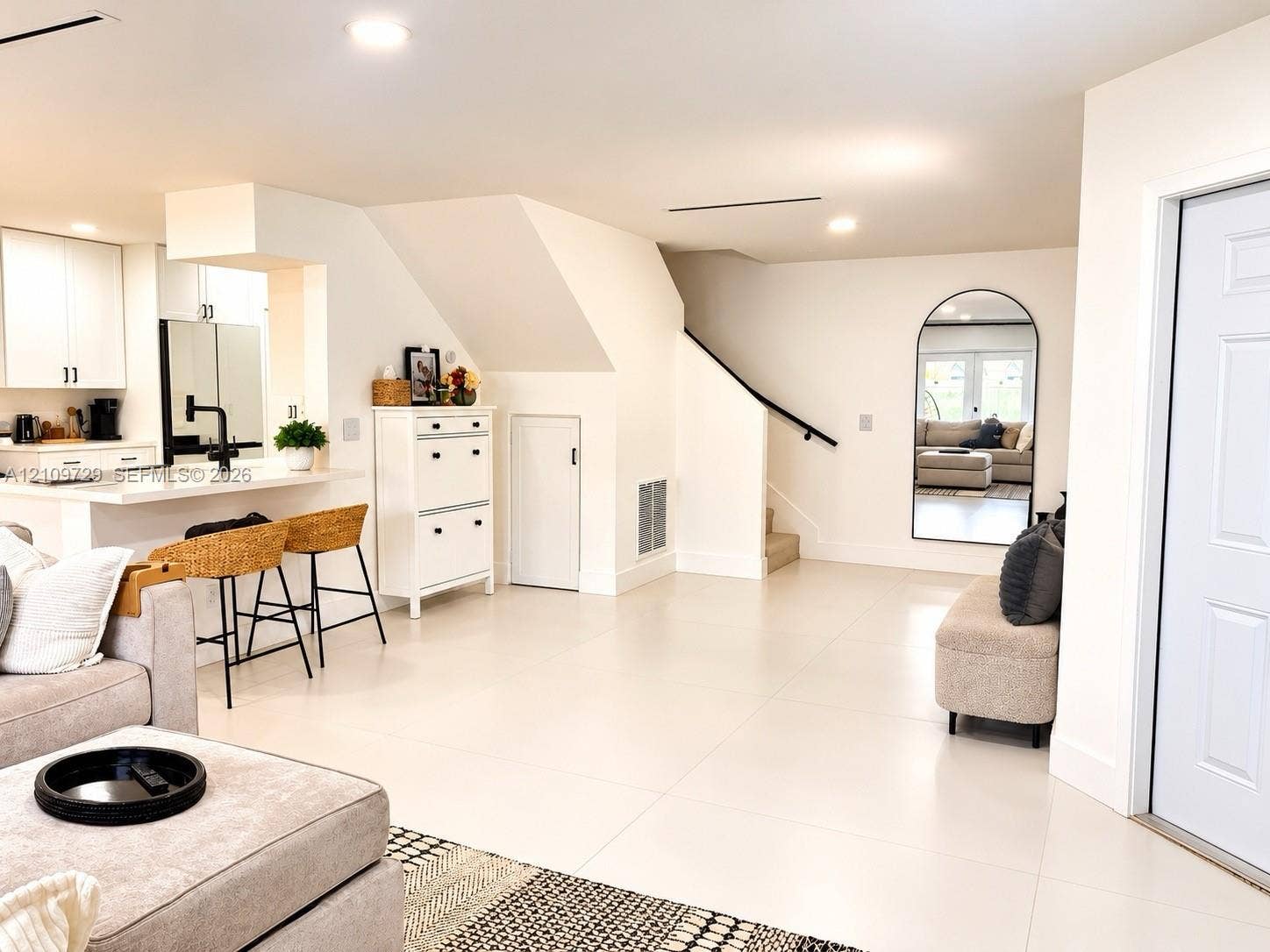 12665 SW 54th Court, Miramar, FL 33027 Open-concept interior featuring large-format tile flooring, recessed lighting, breakfast bar with quartz countertop, and arched wall mirror