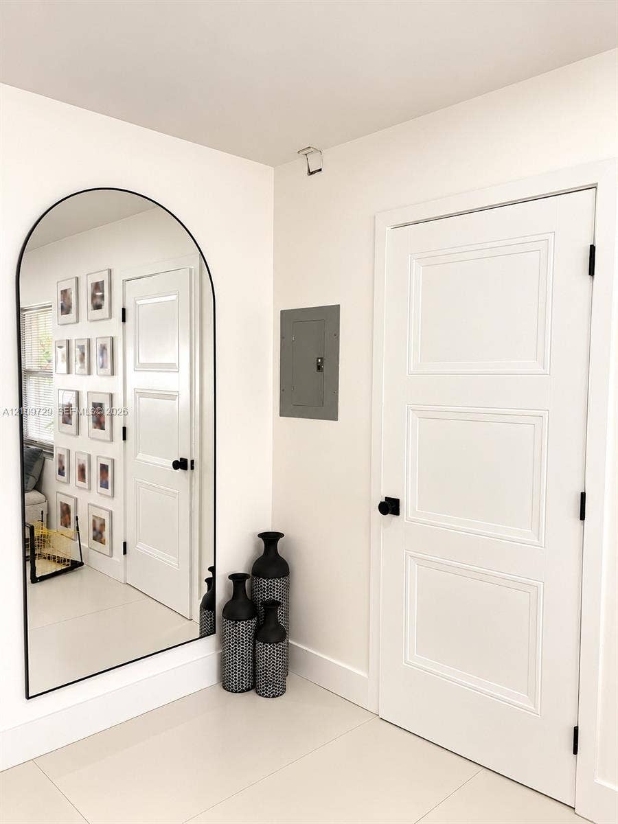 12665 SW 54th Court, Miramar, FL 33027 Arched wall mirror with a black metal frame, three-panel interior door with matte black hardware, and smooth-finish flooring