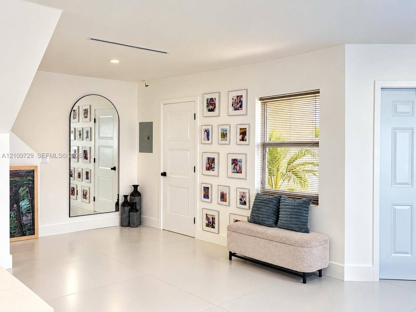 12665 SW 54th Court, Miramar, FL 33027 Neutral-toned tile flooring, arched wall mirror with a slender black frame, recessed ceiling lighting, and solid-core interior doors with matte black hardware