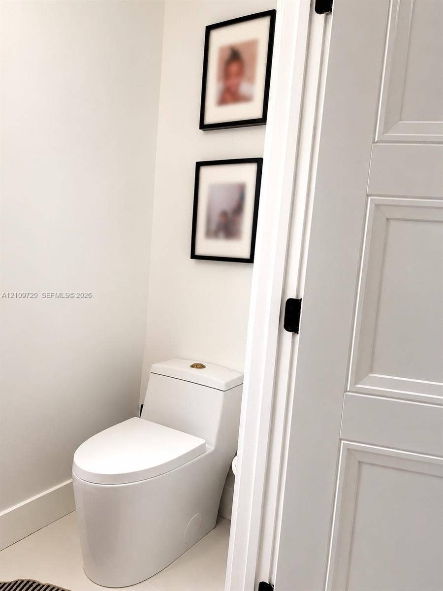 12665 SW 54th Court, Miramar, FL 33027 One-piece dual-flush toilet, solid-core three-panel interior door, and matte black door hardware