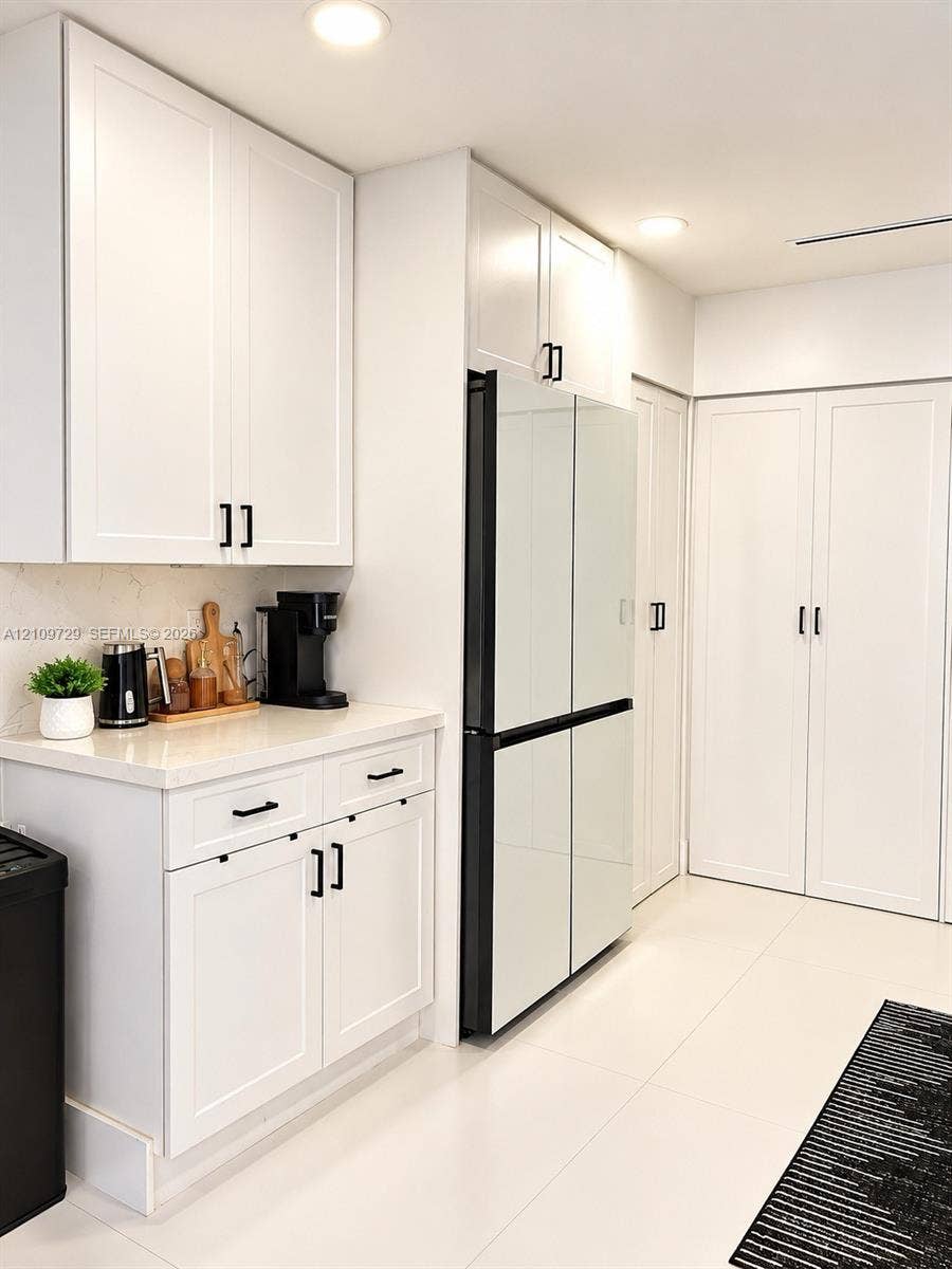 12665 SW 54th Court, Miramar, FL 33027 White shaker-style cabinetry with matte black hardware, stone-surface countertops, floor-to-ceiling pantry storage, and polished tile flooring