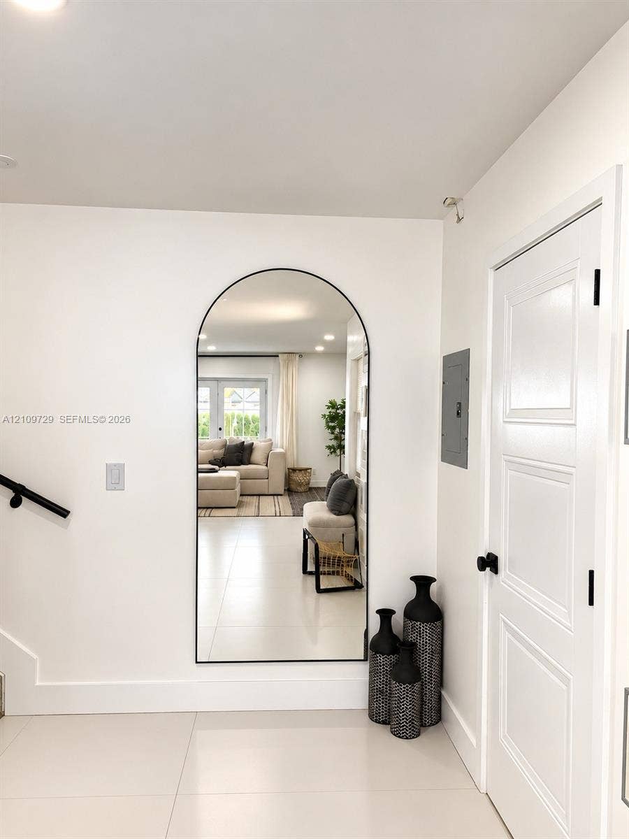 12665 SW 54th Court, Miramar, FL 33027 Large arched wall mirror with a matte black frame, light-toned tile flooring, and a multi-panel door with matte black hardware