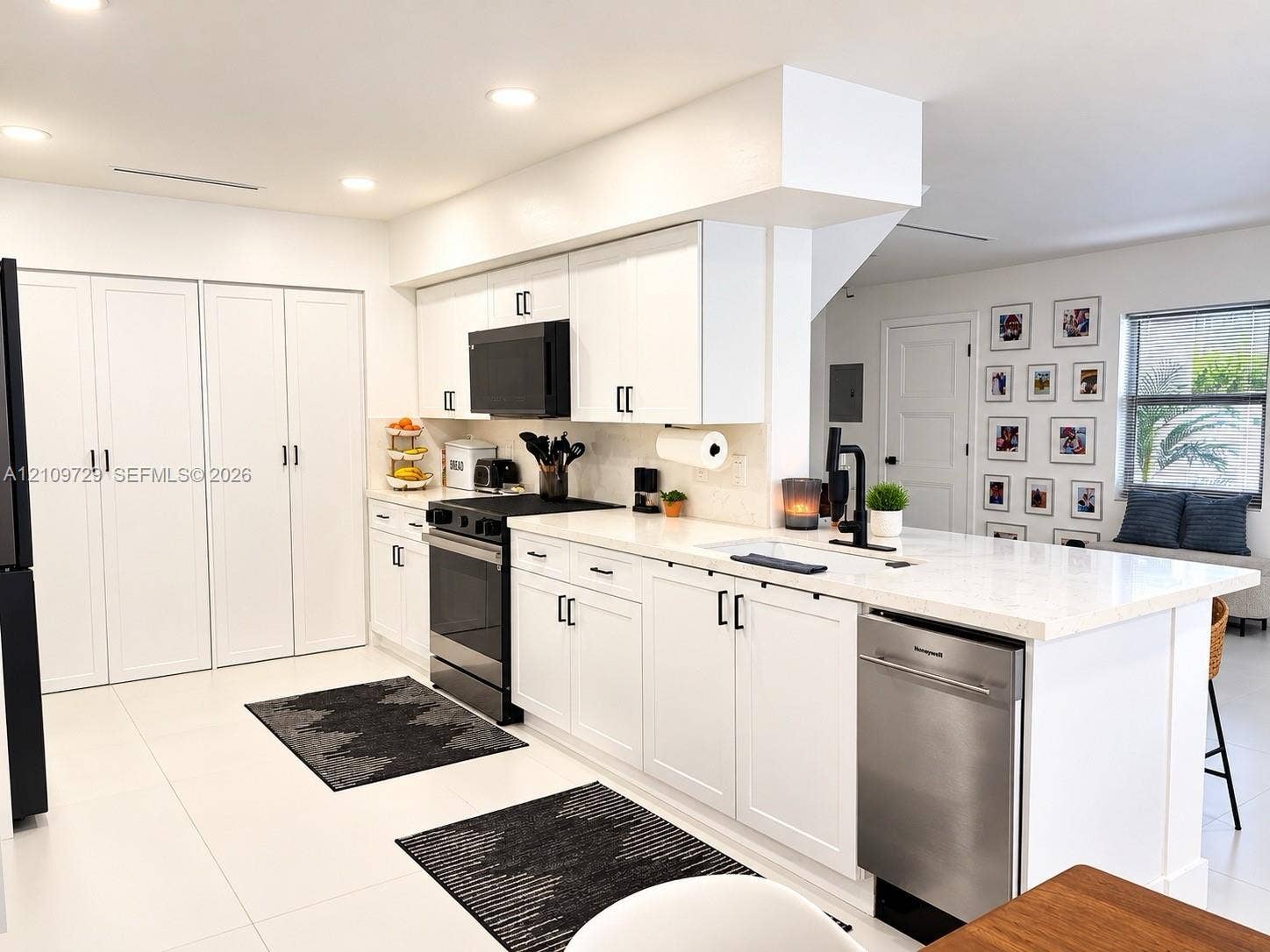 12665 SW 54th Court, Miramar, FL 33027 Kitchen featuring white cabinetry with matte black hardware, stone-surface countertops, a center island with a built-in dishwasher, and a suite of black appliances