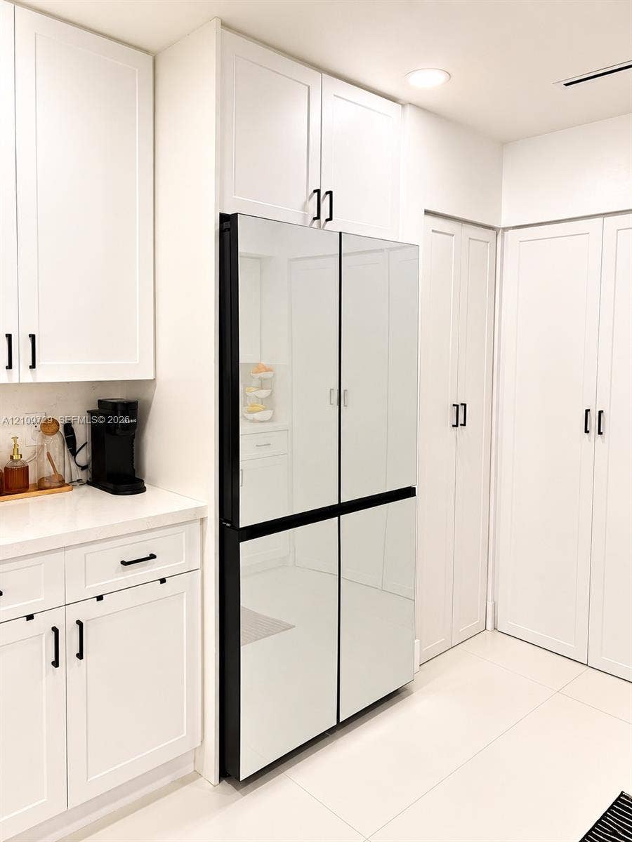 12665 SW 54th Court, Miramar, FL 33027 Custom white cabinetry with matte black hardware, floor-to-ceiling pantry storage, and a four-door refrigerator with mirrored finish panels
