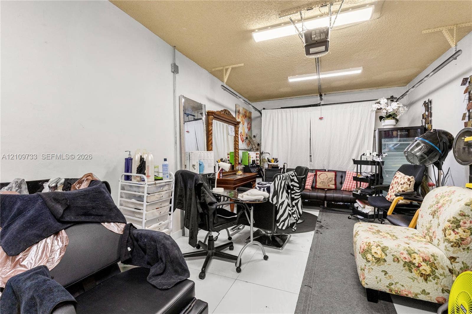 Multi-purpose garage space featuring smooth wall finishes, high-output industrial overhead lighting, and white tile flooring