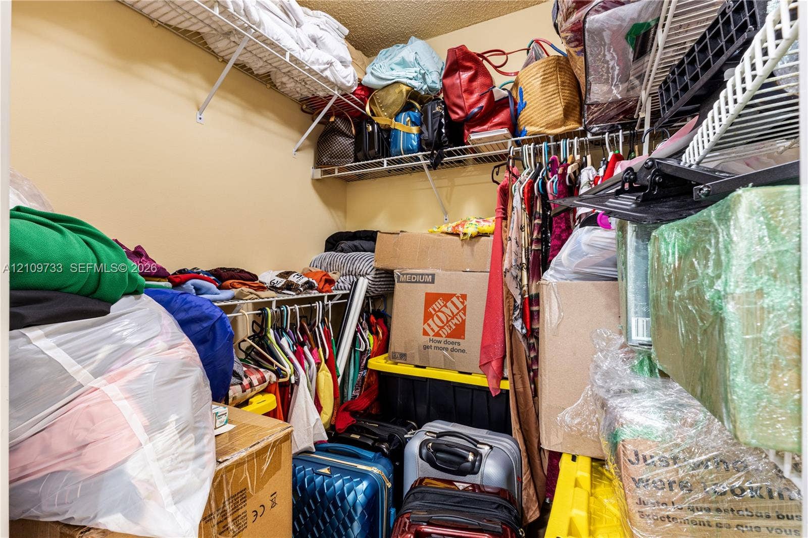 Walk-in storage space featuring multi-level wire shelving and integrated hanging rods