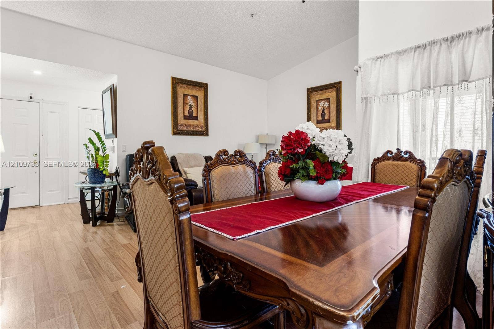 Open-concept living space featuring wood-finish flooring, vaulted ceilings, and natural light via window treatments