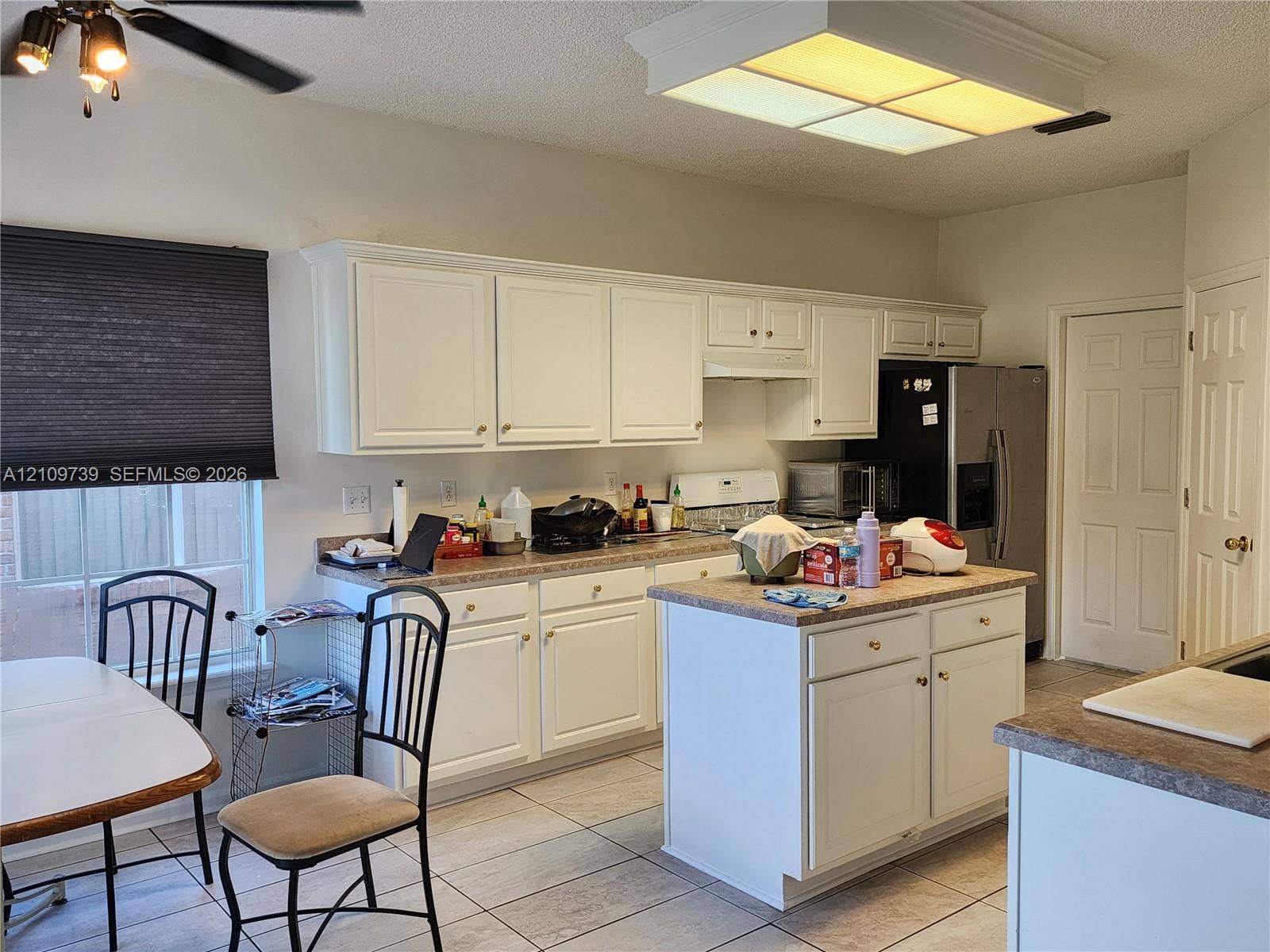 Kitchen featuring white cabinetry, center island, tiled flooring, and a large flush-mount light fixture