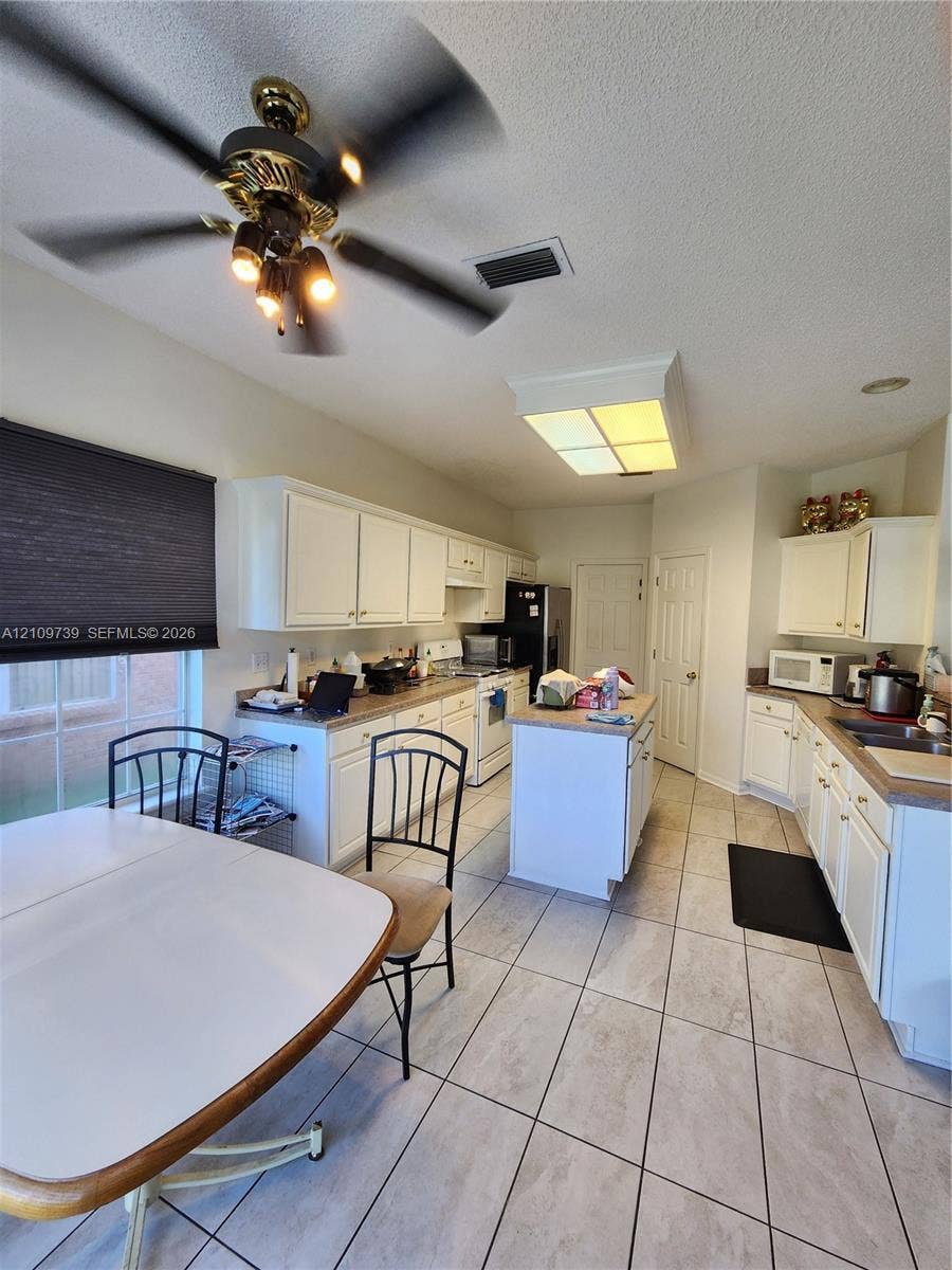 Kitchen featuring white cabinetry, center island, tile flooring, and integrated ceiling lighting