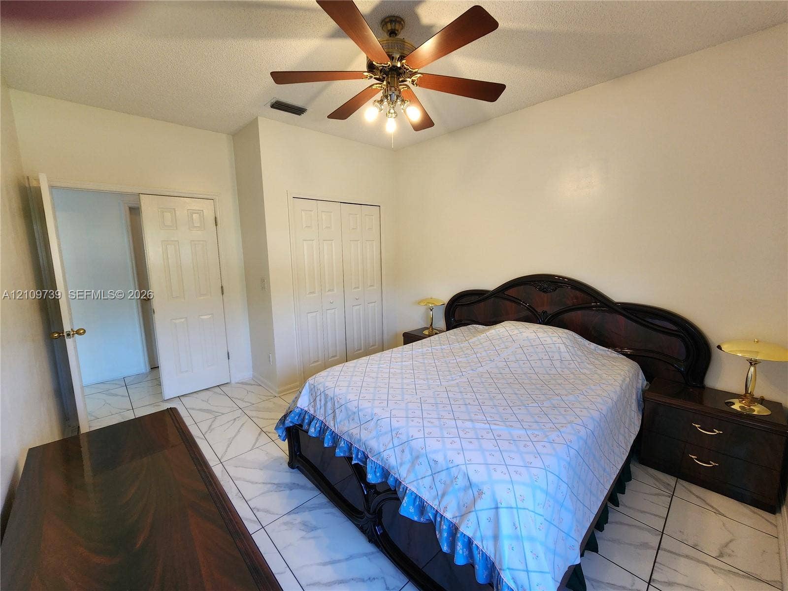Tile flooring with stone-pattern finish, ceiling fan with integrated lighting, and double-door closet