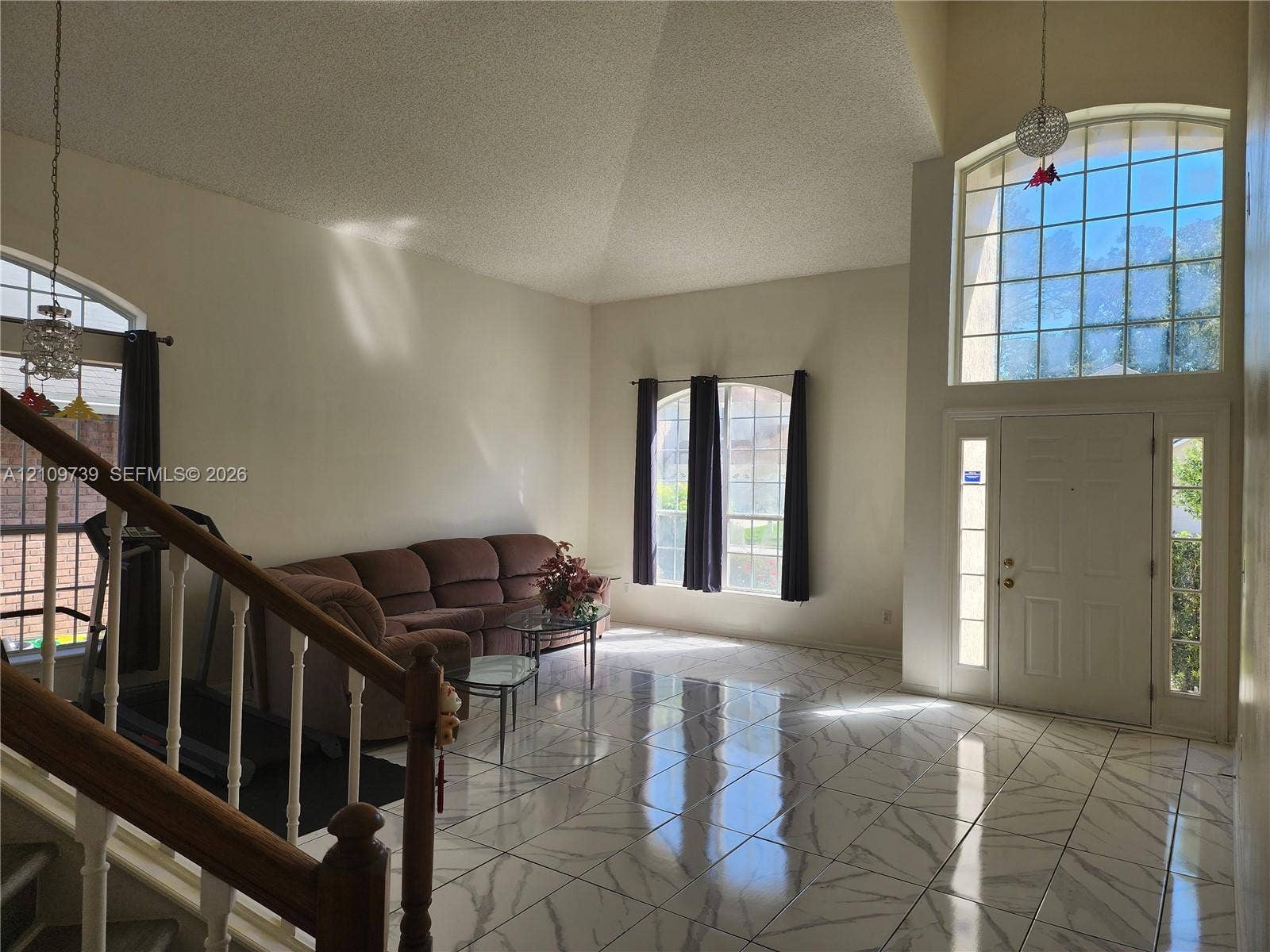 Vaulted ceilings, expansive stone-finish tile flooring, arched windows, and a multi-lite front door with sidelights